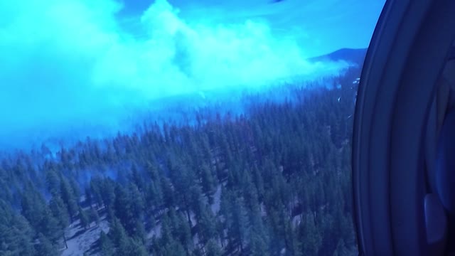 Crew Member Surveys Smokey Forest from a Helicopter