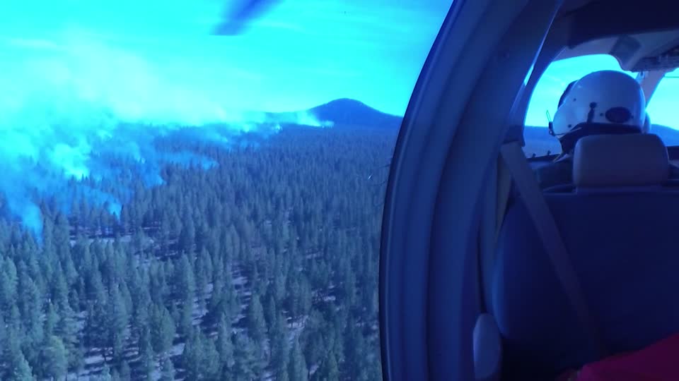 Crew Member Surveys Smokey Forest from a Helicopter